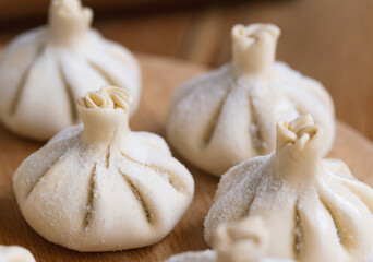 Raw frozen khinkali  on wooden table. Process preparation georgian meal. food concept.