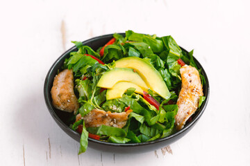 chicken salad with avocado in a black bowl. Healthy food