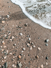 Fototapeta na wymiar A beach with pebbles and wet sand. The coastal wave rolls onto the shore.
