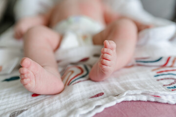 Small children's feet are lying on the bedspread. Cute newborn concept