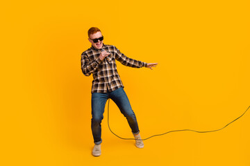 Carefree joyful guy in shirt holding microphone singing karaoke feeling happy enjoy isolated yellow background