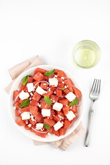 Summer salad of watermelon, feta cheese and mint on a white background, top view.