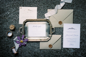 Wedding invitations lie next to envelopes and a tray