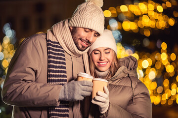 winter holidays, hot drinks and people concept - happy young couple with takeaway coffee cups in...