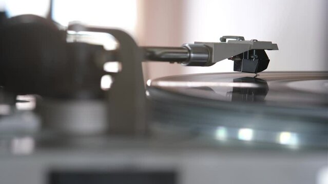 Focus on The Headshell Cartridge and Stylus of Classic Vintage Vinyl Record Player from behind and Playing on Vinyl Record Music