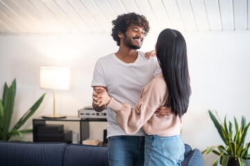 Fototapeta premium A young couple smiling and dancing in the room