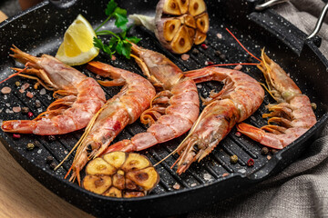 Delicious shrimp with seasoning, Prawns fried with splashes of lemon juice in a freeze motion on a dark background. Seafood appetizer. Culinary, cooking concept