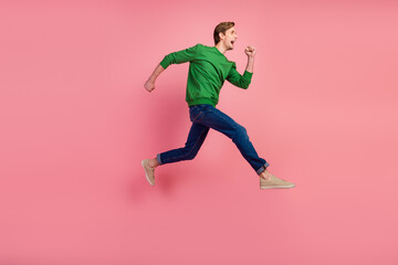 Fototapeta na wymiar Full length portrait of excited young man in shirt jumping fast running isolated over pastel color background