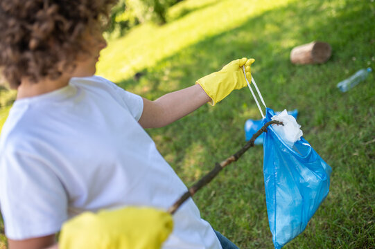 Teen Holding A Stick And Gethering The Litter On The Grass