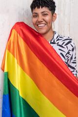 Ethnic woman leaning back with rainbow flag on pavement