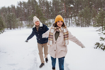 Fototapeta na wymiar people, love and leisure concept - happy smiling couple walking in winter forest