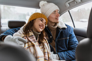 people, love and leisure concept - happy smiling couple hugging on car back seat in winter