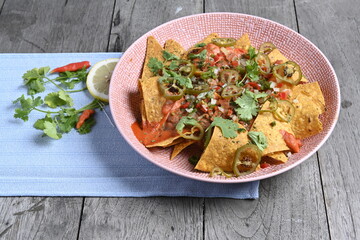 Corn chips nachos with fried minced meat with sauce on wooden background.