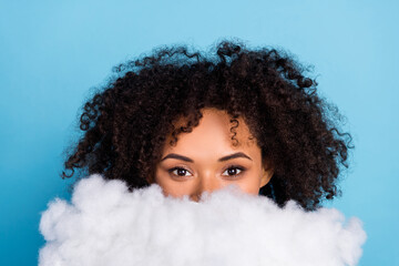 Portrait of attractive funny girly girl hhiding face behind white cloud isolated over bright blue...
