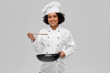 food cooking, culinary and people concept - happy smiling female chef with frying pan over grey...