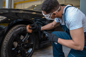 Service station worker polishing the car tire