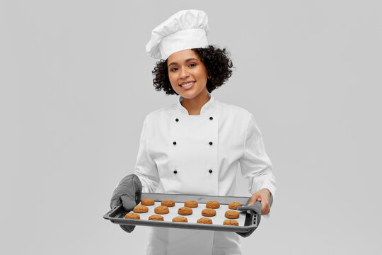 Young african american cooker girl wearing uniform and hat holding tray  with dome pointing and showing with thumb up to the side with happy face  smiling Stock Photo