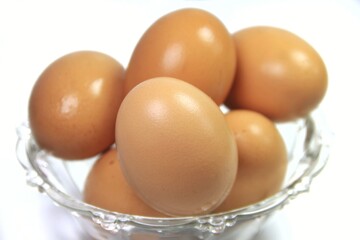 Close-up of chicken eggs arranged in a clear glass cup.
