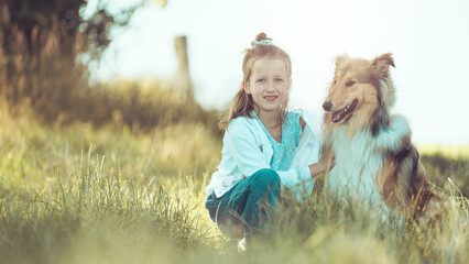 Junges blondes Mädchen mit schottischem Collie sable white im Sommer zusammen auf einer Wiese...