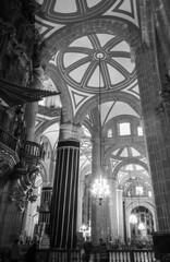 Vertical view in black and white of the interior of the Metropolitan Cathedral of Mexico City with many people entering and leaving admiring the beautiful architecture