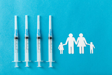 medicine, vaccination and healthcare concept - disposable syringes and family pictogram on blue...