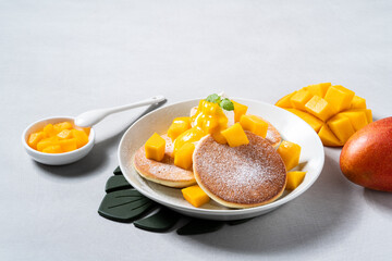 Delicious Japanese souffle pancake with dice mango and jam on white table background.