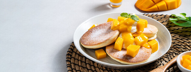 Delicious Japanese souffle pancake with dice mango and jam on white table background.