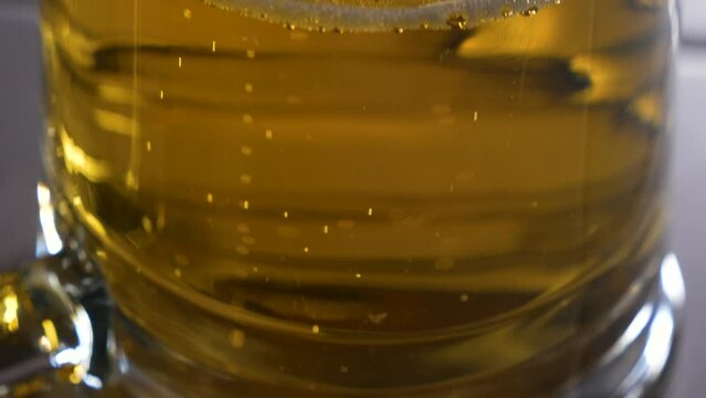 Beer in a glass with bubbles rising to the top. Camera view panning upward.