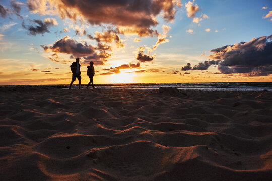 Tourists walk on the beach during sunset over the Baltic Sea