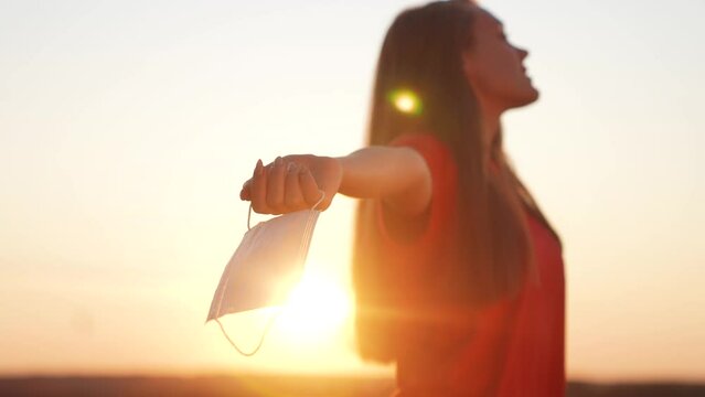 the girl took off the mask holds in her hand on the nature in the park. freedom coronavirus end of pandemic concept. free girl holding a protective mask in her hand. end of the covid pandemic