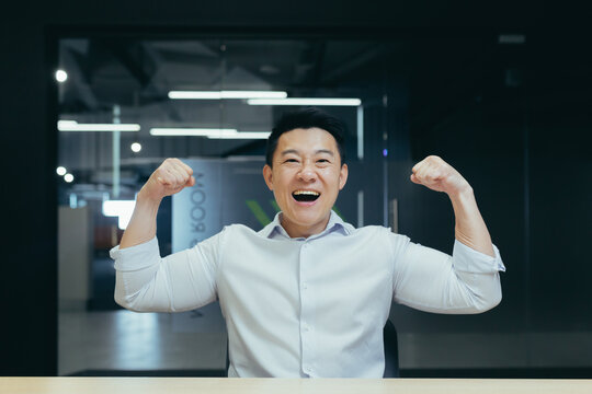 Asian super hero businessman looking at camera and smiling holding hands up gesture of strength and confidence man working in office at work