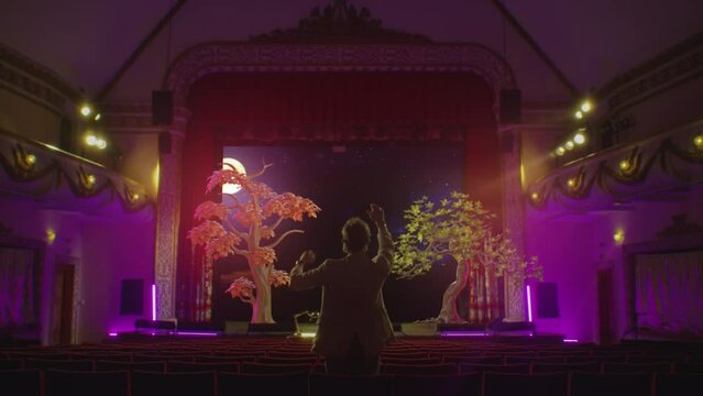 Innovation technology concept for creative: A director in a theater in a vr headset uses augmented reality software to simulate and create scenery in a 3d virtual space for a future performance.