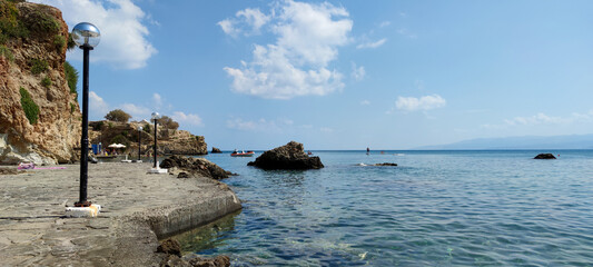 View of a sea coast with a blue sky and rocks	