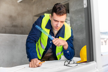 architecture, construction business and people concept - male architect with blueprint and ruler working at office