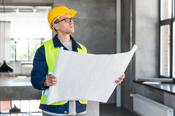 architecture, construction business and people concept - male architect in helmet with blueprint at office