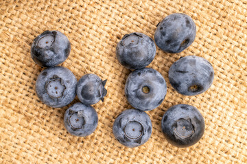 Organic blueberry berries on jute fabric, close-up, top view.