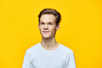 portrait of a smiling guy on a yellow background in a white T-shirt
