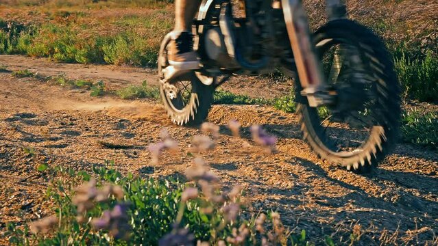 Motocross biker rides on sandy track on Powerful enduro motorcycle kicking up dust in slow motion. Concept of active lifestyle.