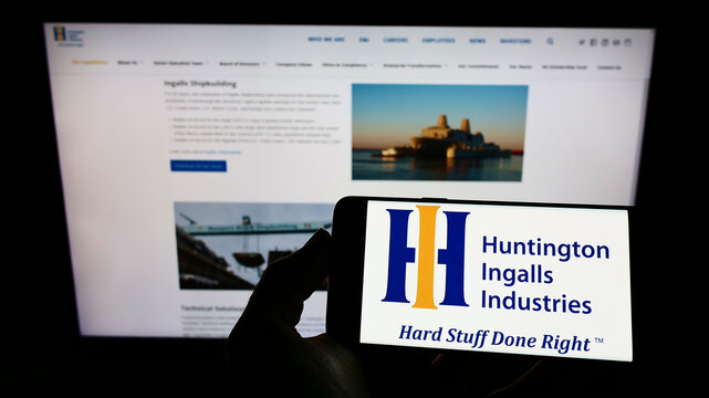 Stuttgart, Germany - 01-16-2022: Person holding cellphone with logo of US company Huntington Ingalls Industries Inc. (HII) on screen in front of web page. Focus on phone display.