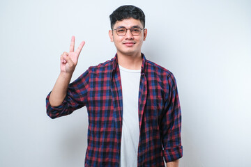 Fototapeta premium Young handsome Asian man wearing casual clothes showing and pointing up with fingers number two while smiling confident and happy