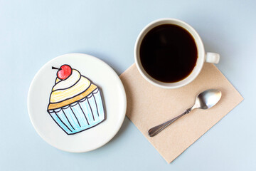 A cupcake drawn with colored pencils  lying on a red napkin and a white cup of black coffee in out...