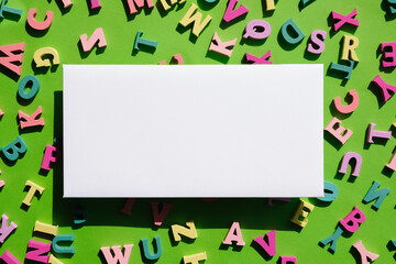 White blank horizontal paper card scattered multi-colored letters on a bright green background....