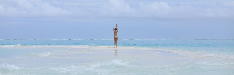 beautiful brunette girl in a green swimsuit on the shore of a tropical island
