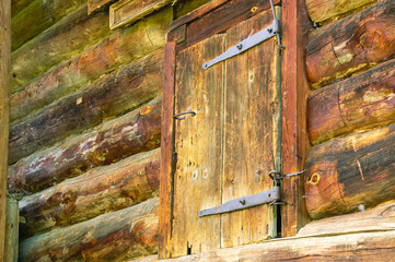 The wooden door of an old house built in the 19th century. Forged steel hinges on the antique door of the house. Wooden architecture in the countryside.