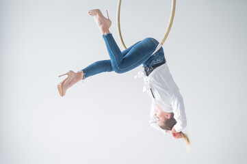 Caucasian woman in casual clothes on an aerial hoop. 