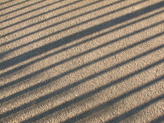 Shadow line of fence on concrete floor