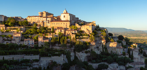 Gordes, panoramic view of one of the most well-known hilltop villages of Provence at sunset. Unique architecture of stone houses and terraces in Vaucluse, Provence-Alpes-Cote d'Azur region, France - obrazy, fototapety, plakaty