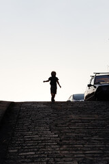 The boy runs up the cobbled street.
