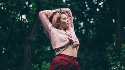 Beautiful girl under the summer rain in the park