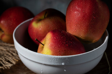 Wet red apples in a white ceramic cup